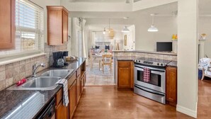 Una cocina con encimeras de granito, electrodomésticos de acero inoxidable, armarios de madera y un comedor con mesa y sillas.