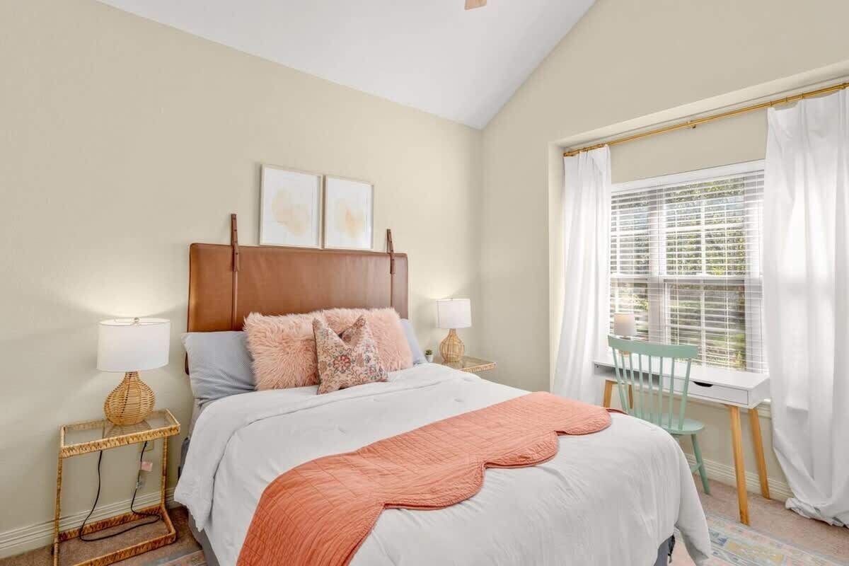 Une chambre à coucher avec un lit, des tables de chevet, une fenêtre avec des rideaux et une chaise.