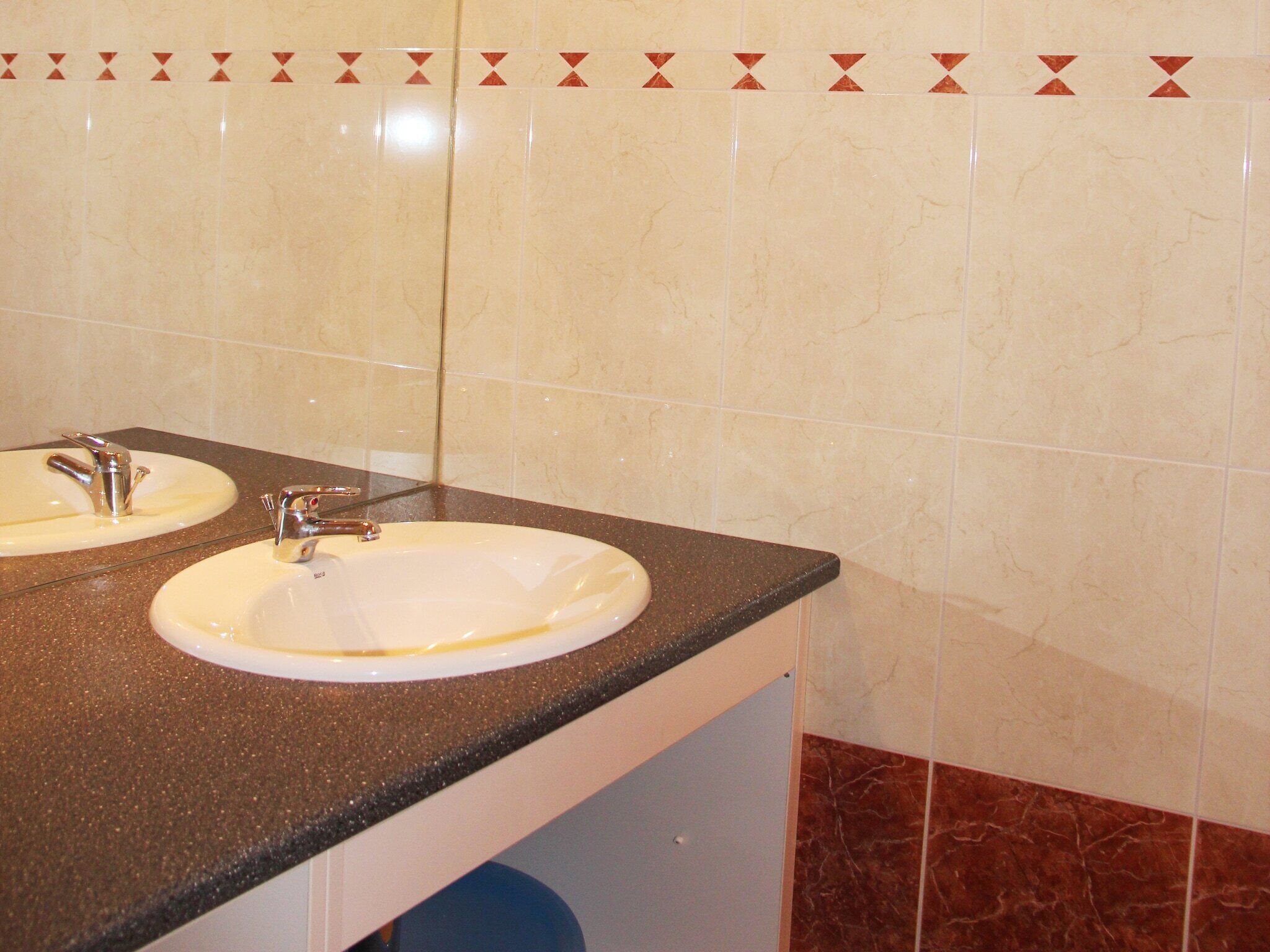 A bathroom with two sinks, a mirror, and a tiled wall.