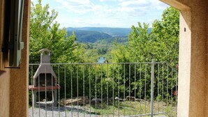 A view through an arched doorway overlooking a valley with a stone barbecue grill and a metal fence. - Villa near Les Vans Centre (Les Vans)