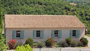 A two-story building with a tiled roof and light-colored walls, surrounded by lush greenery and hills in the background. - Villa near Les Vans Centre (Les Vans)