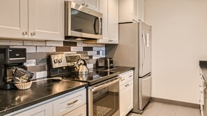 A modern kitchen with stainless steel appliances, white cabinetry, and a tiled backsplash. - Newly Updated Condo, Pool & Hot Tub, Shuttle to Slopes, Large Private Patio (Keystone)