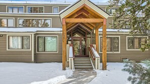 A building with a covered entrance and a snow-covered ground. - Newly Updated Condo, Pool & Hot Tub, Shuttle to Slopes, Large Private Patio (Keystone)