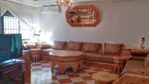 A traditional living room with a checkered floor, a sofa set, a coffee table, and a television.