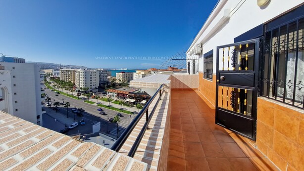 An apartment with a balcony overlooking a cityscape and the sea.