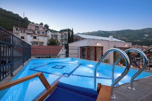A rooftop swimming pool with a view of the city and hills in the background. - Twelve (Budva)