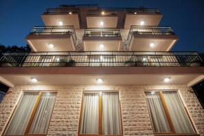 A multi-story building with balconies, large windows, and a stone facade.