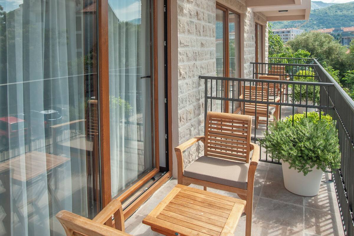 A balcony with wooden furniture, a potted plant, and a view of the landscape.