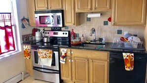 A kitchen with wooden cabinets, a stainless steel oven, a microwave, and a sink.