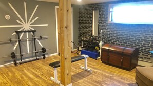 A gym with a wooden bench, weightlifting equipment, and a mirror.