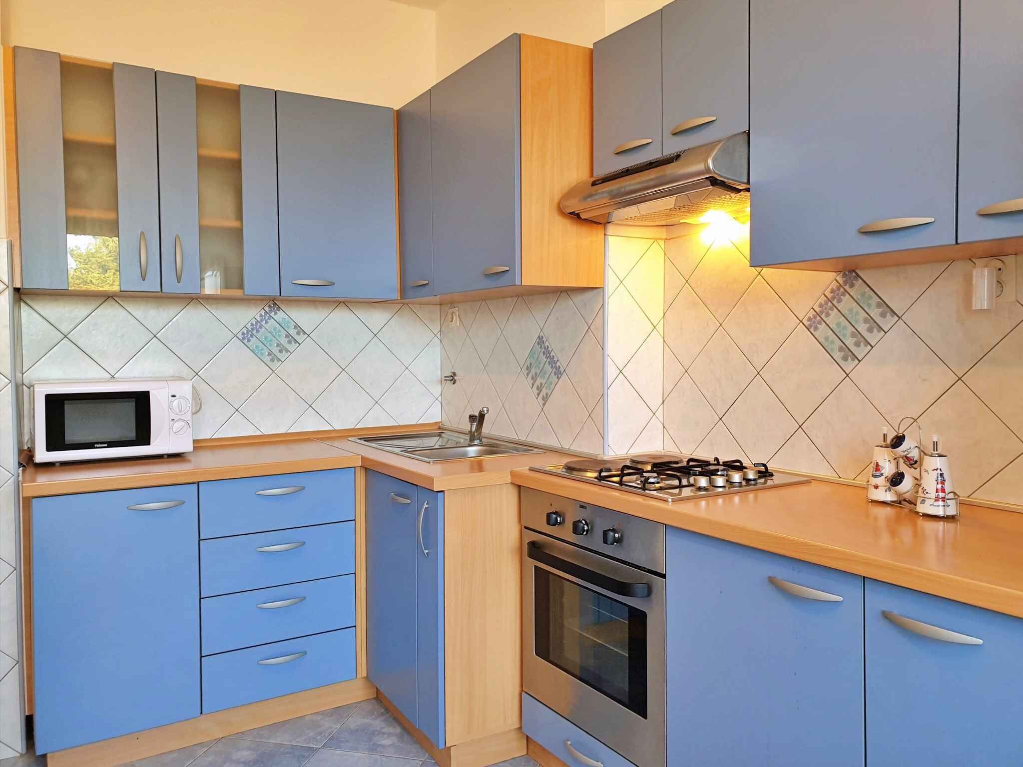 A modern kitchen with blue cabinets, a microwave, a gas stove, and a tiled backsplash.
