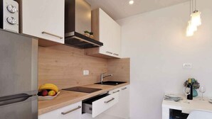 A modern kitchen with a built-in oven, a stainless steel sink, and wooden cabinetry. - Holiday flat with sea view just 60 m from the beach (Šilo)