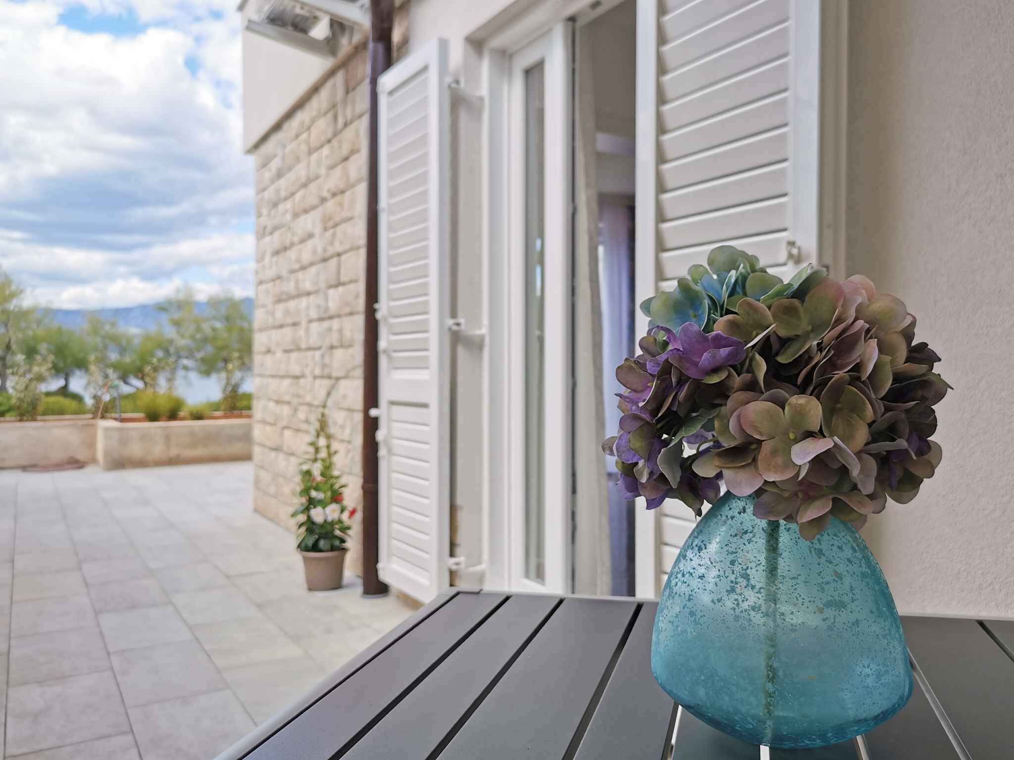 A table with a vase of flowers on a balcony.
