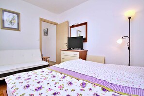 Cozy retreat with a bed, flat-screen TV, and floor lamp.