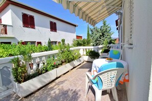 Enjoy al fresco dining in a serene outdoor space surrounded by lush greenery and a charming Mediterranean-style building.