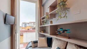 A bedroom with a bed, a TV, and shelves with plants and decorative items.