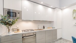A modern kitchen with white cabinets, a built-in oven, a gas stove, and a microwave.