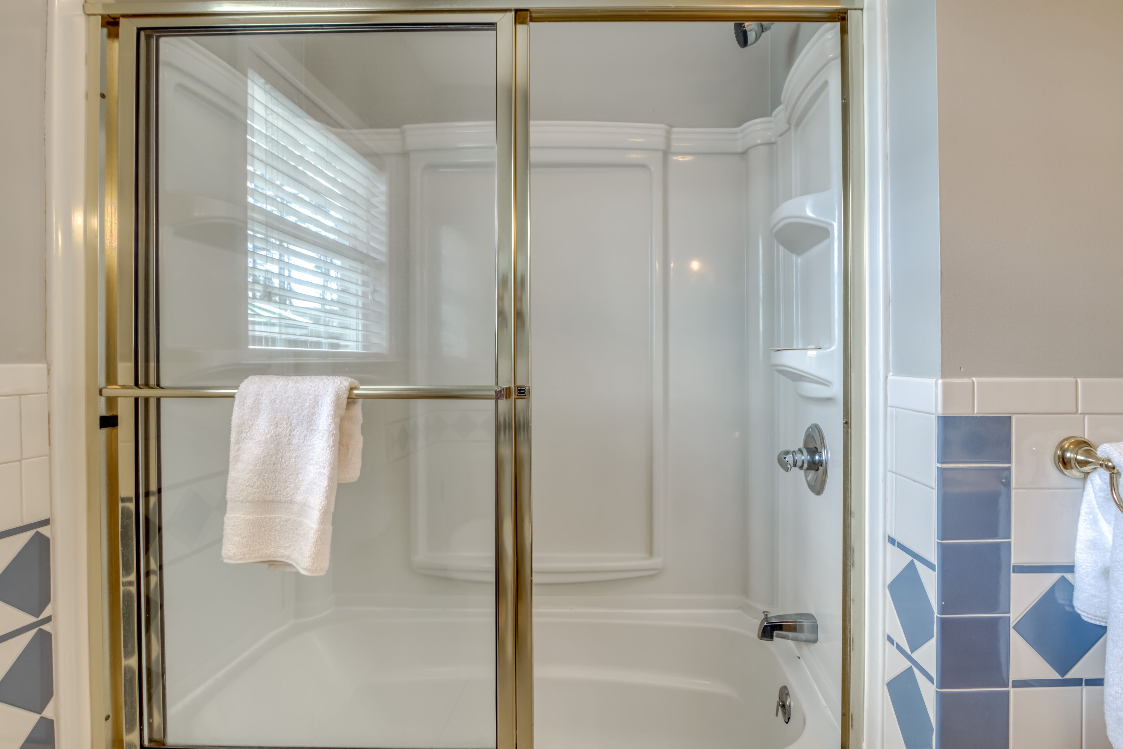 A glass-enclosed shower with a white towel hanging on the door handle.
