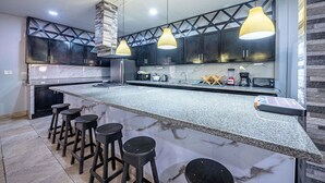 A modern kitchen with dark cabinets, a marble countertop, and three pendant lights. - Party like a King, Close to Jaco Center in the ultimate party pad!        (Jacó)