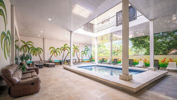 A spacious indoor area with a pool, reclining chairs, and a balcony. - Party like a King, Close to Jaco Center in the ultimate party pad!        (Jacó)