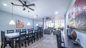 A spacious dining area with a high ceiling, pendant lights, and a large window providing natural light. - Party like a King, Close to Jaco Center in the ultimate party pad!        (Jacó)