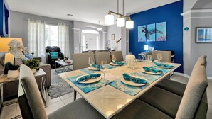 Ein Essbereich mit einem für vier Personen gedeckten Tisch, einer Chandelüster und Kunstwerken an den Wänden.