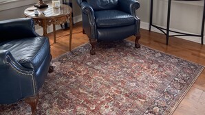 A living room with a leather armchair, a blue sofa, a patterned rug, a lamp, and a small table with decorative items. - Historic Bungalow in the Heart of the City (Mission,)