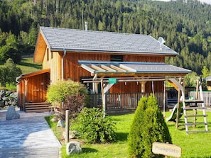Eine Holzhütte mit einer Veranda und einem Kiesweg, ein Schild zeigt 'Parkplatz'.