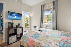 A bedroom with a bed, a television, a desk, and a window with curtains. - Cozy Studio - 20 minutes from Disney - LOWEST price in Regal Palms Resort (Davenport)