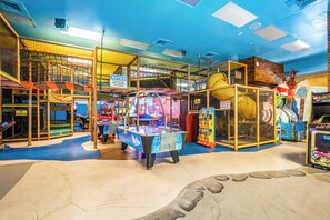 Un espace de jeux intérieur comprenant divers jeux d’arcade et une table de billard.
