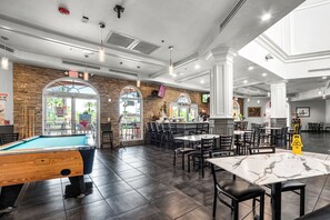 A spacious indoor area with a pool table, dining tables, and chairs. There are multiple exits and a visible emergency exit sign. - Cozy Studio - 20 minutes from Disney - LOWEST price in Regal Palms Resort (Davenport)
