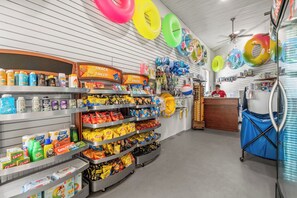 A snack aisle with various chips and snacks, a cashier counter, and a ceiling with hanging decorations. - Cozy Studio - 20 minutes from Disney - LOWEST price in Regal Palms Resort (Davenport)