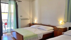 Una habitación de hotel con cama, mesitas de noche y una ventana con cortinas.