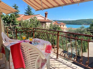 Ein Balkon mit Tisch für zwei Personen, mit Blick auf einen malerischen See und Hügel.