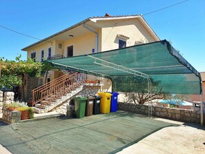 Ein Haus mit einer grünen Markise, einer Steinstufe und einem kleinen Gartenbereich mit Topfpflanzen.