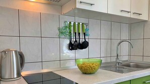 Una cocina moderna con un hervidor de acero inoxidable, un tazón verde y una tabla de cortar negra sobre la encimera.