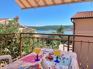 En balkon med et bord dækket til to, med udsigt over et naturskønt sølandskab og bakker.