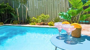 Une piscine avec deux boissons sur une table.