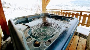A hot tub in a wooden cabin with a wooden deck and a snowy mountain view. - A L'orée du Bois (Dommartin-lès-Remiremont)