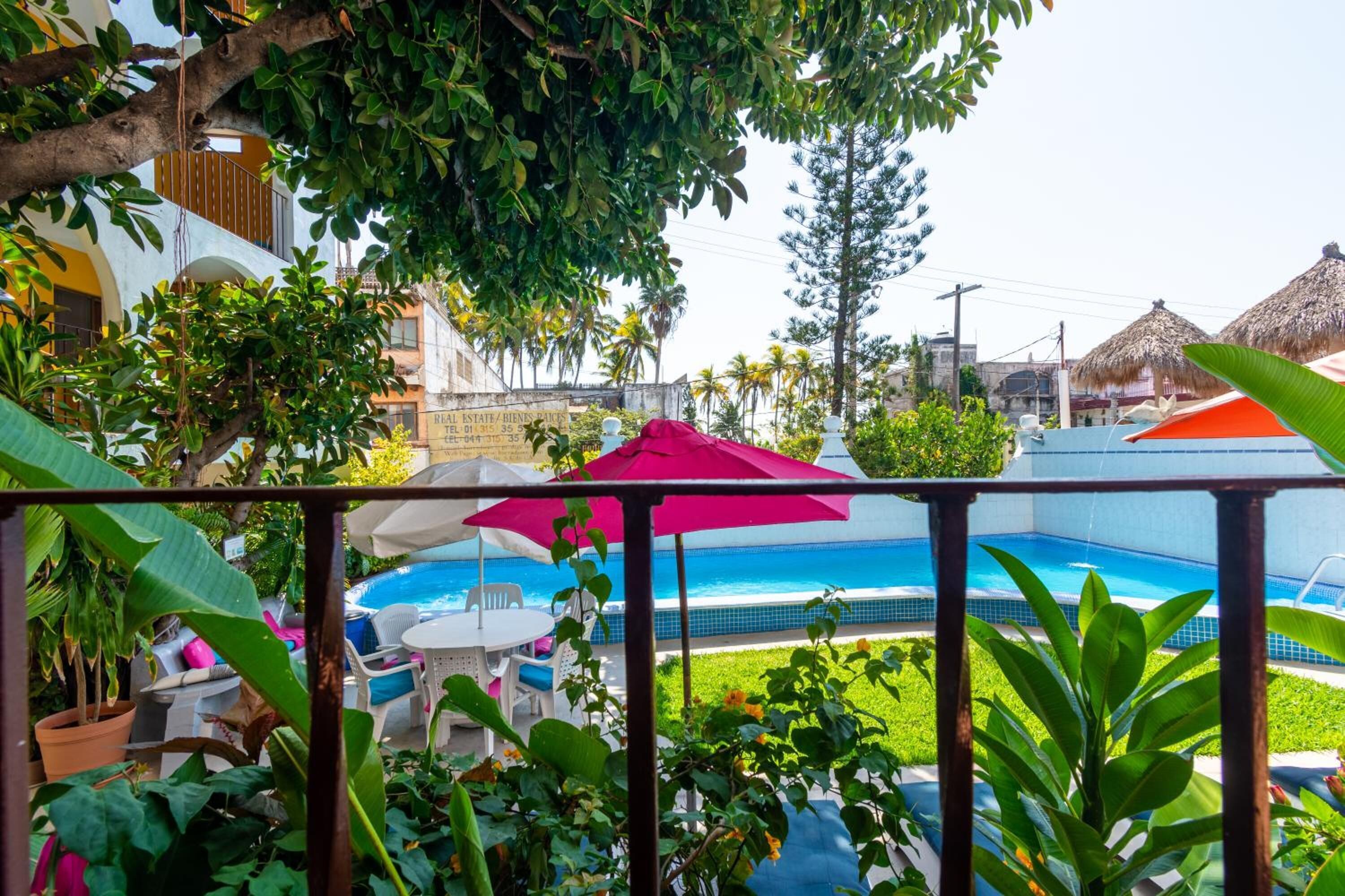 Un espace piscine offrant une vue sur un bâtiment et une construction à toit de chaume.