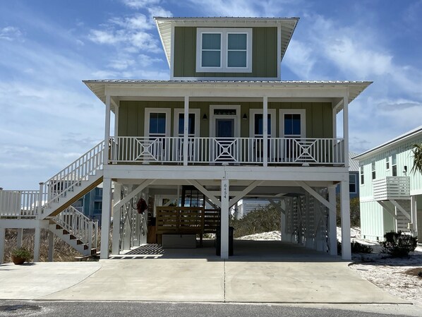 A two-story house with a balcony, a covered porch, and a staircase leading to the upper level.