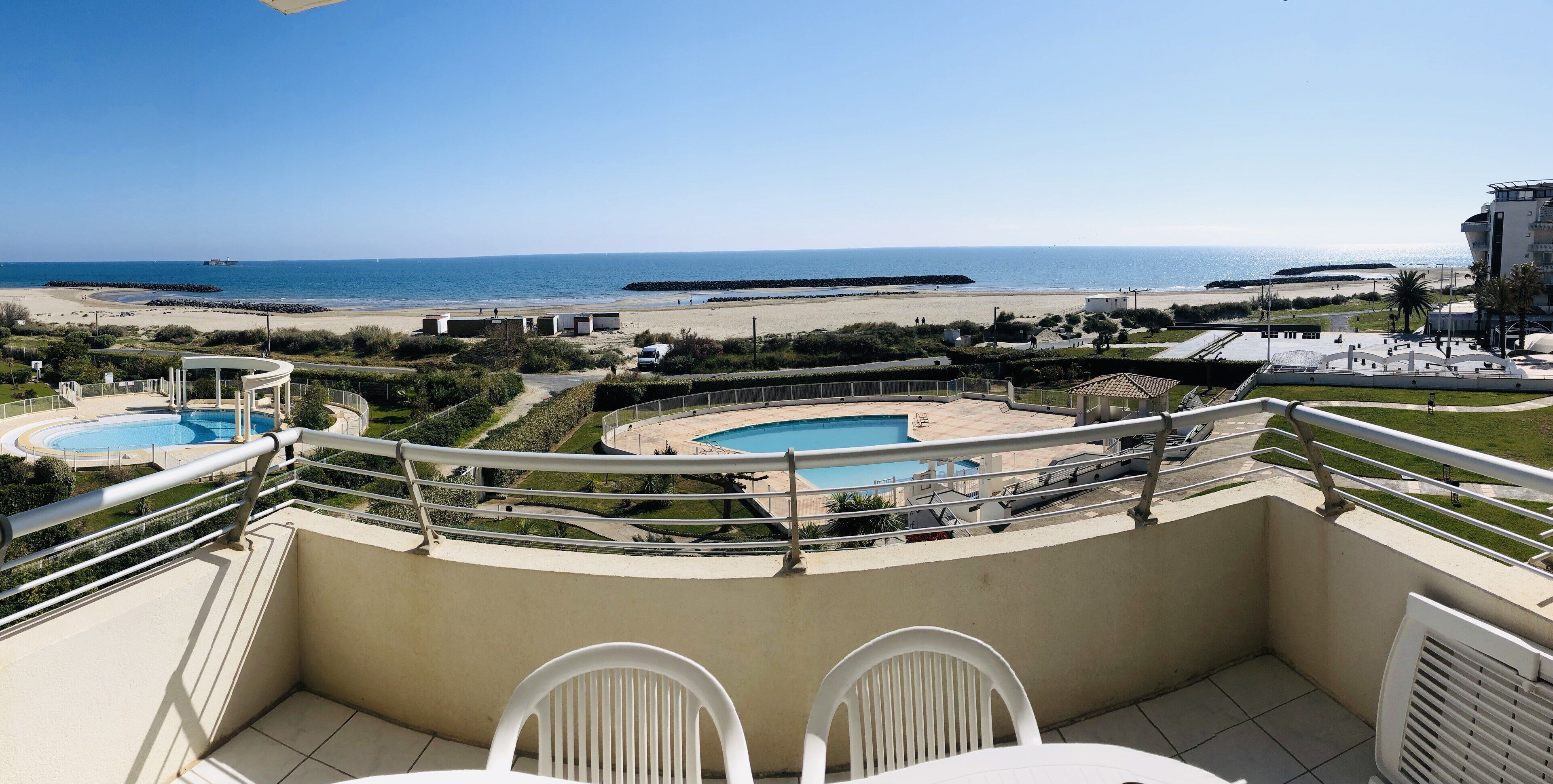 Een balkon met uitzicht op een strand en een zwembad.