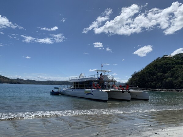 Un ferry accosta dans un port tranquille, sous un ciel dégagé, avec un paysage vallonné en arrière-plan.
