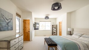 A bedroom with a bed, bench, dresser, and a TV on the wall. - Big Sky Escape - Spacious Home with Hot Tub (Big Sky)