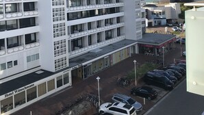 A multi-story hotel with a modern design, featuring balconies and a parking area in front. - Bright, cozy vacation apartment in a perfect location close to the beach and town center  (Sylt)