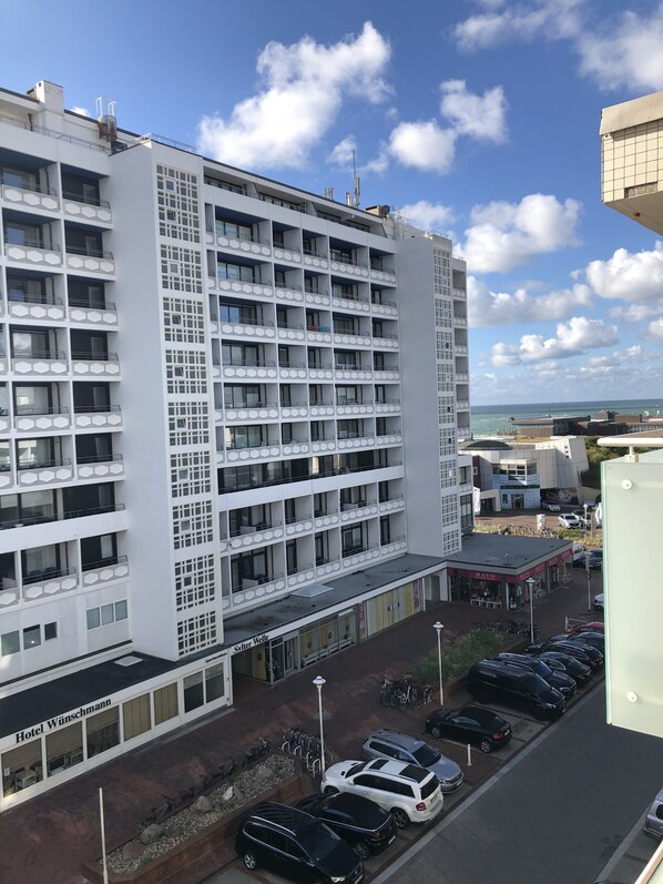 A multi-story hotel with a modern design, featuring balconies and a parking area in front. - Bright and cozy vacation apartment, perfectly located near the beach and downtown (Sylt)