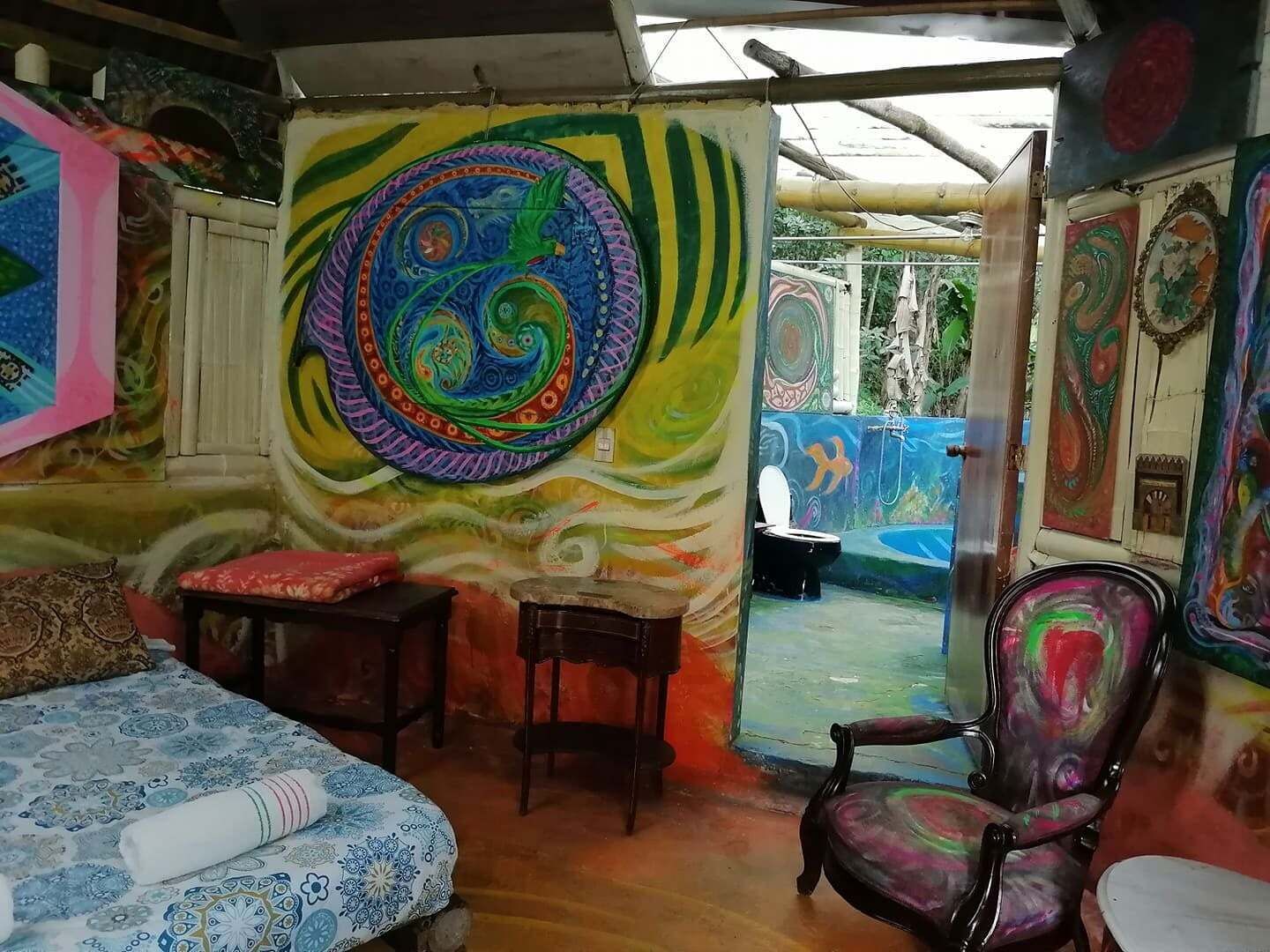 Une pièce avec une fresque murale colorée, un lit, une chaise et une petite table.