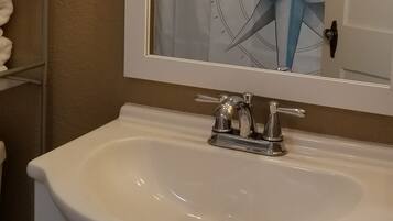 Een bad/douchecombinatie, een haardroger, handdoeken, zeep