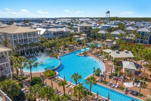 Un resort con una gran piscina central, varios balcones y palmeras.