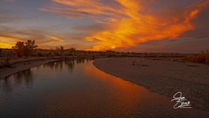 Um rio refletindo um pôr do sol sob um céu limpo.
